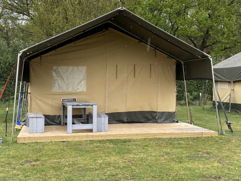 Tienda Safari XL en Holiday Park Duinhoeve, Países Bajos, con terraza de madera, mesa y bancos delante.