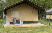 Tienda Safari XL en Holiday Park Duinhoeve, Países Bajos, con terraza de madera, mesa y bancos delante.