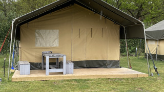 Safari-Zelt XL im Holiday Park Duinhoeve, Niederlande, mit Holzterrasse, Tisch und Bänken davor.