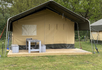 Safari-Zelt XL im Holiday Park Duinhoeve, Niederlande, mit Holzterrasse, Tisch und Bänken davor.