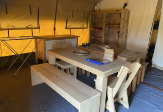 Binnenkant van Safari tent XL met houten meubels in Holiday Park Duinhoeve in Nederland.