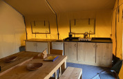 Indretning af Safari telt XL i Holiday Park Duinhoeve, Holland, med køkken, spisebord og træmøbler.