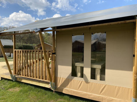 Glamping Deluxe type 2-lodge bij Holiday Park Duinhoeve in Nederland, met houten veranda en tentdoek.
