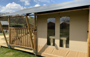 Glamping Deluxe Typ 2 Lodge im Holiday Park Duinhoeve, Niederlande, mit Holzveranda und Zeltdach.