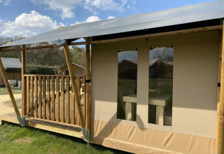 Lodge Glamping Deluxe tipo 2 en Holiday Park Duinhoeve, Países Bajos, con porche de madera y tienda de lona.