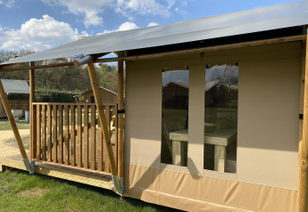 Glamping Deluxe Typ 2 Lodge im Holiday Park Duinhoeve, Niederlande, mit Holzveranda und Zeltdach.