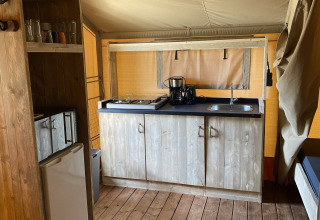 Køkkenområde i Glamping Deluxe type 2 på Holiday Park Duinhoeve med træskabe og gaskomfur.