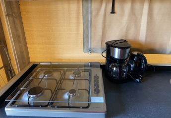 Estufa y cafetera en el área de cocina de Glamping Deluxe tipo 2 en Holiday Park Duinhoeve, Países Bajos.