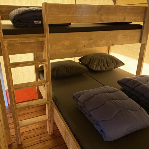 Litera con ropa de cama negra en Glamping Deluxe tipo 2 en Holiday Park Duinhoeve, Países Bajos.