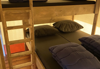 Køjeseng med sort sengetøj på Glamping Deluxe type 2 ved Holiday Park Duinhoeve, Holland.