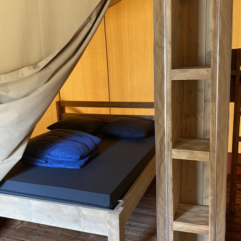 Vista interior de un lodge Glamping Deluxe tipo 2 con muebles y cama de madera en Holiday Park Duinhoeve.