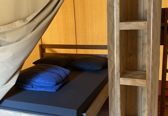 Indvendigt billede af en Glamping Deluxe type 2 lodge med træmøbler og seng i Holiday Park Duinhoeve.