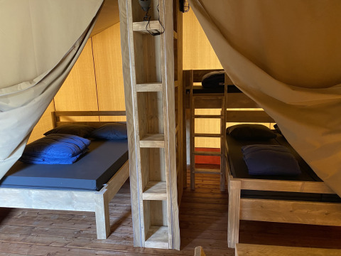 Vista interior de la cabaña Glamping Deluxe tipo 2 con camas de madera en Holiday Park Duinhoeve, Países Bajos.