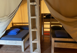 Vista interior de la cabaña Glamping Deluxe tipo 2 con camas de madera en Holiday Park Duinhoeve, Países Bajos.