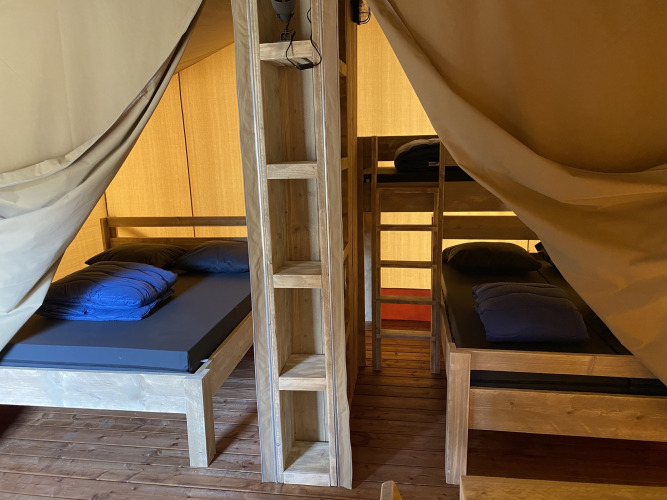 Interieurfoto van Glamping Deluxe type 2 lodge met houten bedden in Holiday Park Duinhoeve in Nederland.