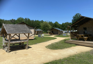 Glamping Deluxe Typ 2 Lodge im Holiday Park Duinhoeve, Niederlande, mit Zelten und Picknicktischen im Grünen.