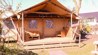 Safaritent DeLuxe op Camping Vossenberg in Nederland, met houten terras en zitbank buiten.