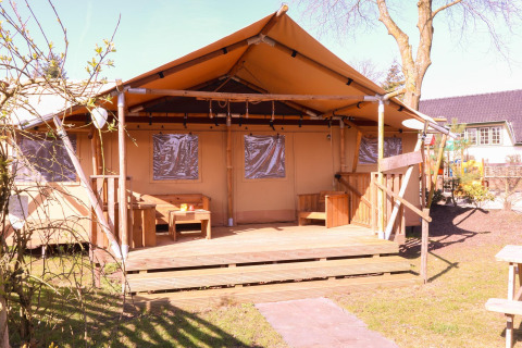 Safari-Zelt DeLuxe auf dem Campingplatz Vossenberg in den Niederlanden, mit Holzterrasse im Freien.