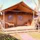 Tienda Safari DeLuxe en Camping Vossenberg, Países Bajos, con terraza de madera y asientos exteriores.
