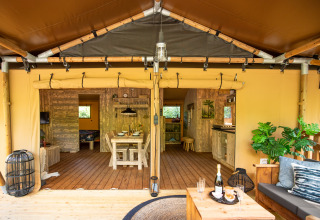 Interior view of deluxe safari tent at Camping Vossenberg in the Netherlands, featuring dining and lounge area.