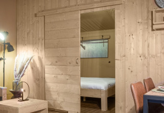 Interior view of the Safari tent DeLuxe at Camping Vossenberg, Netherlands, featuring wooden walls and decor.
