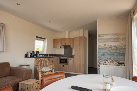 Binnenzicht van de Dune Lodge Family op Camping Zonneweelde in Nederland met moderne keuken en zithoek.