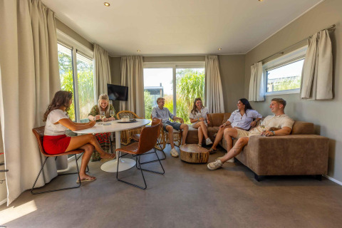 Grupo de amigos relajándose en Dune Lodge Family en Camping Zonneweelde, Países Bajos, sala de estar.