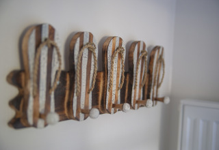 Decoración de pared con percheros en forma de sandalias a rayas en Dune Lodge Family, Camping Zonneweelde.
