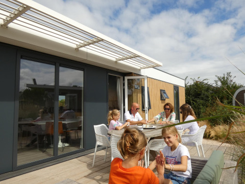 Familie entspannt sich im Freien am Dune Lodge Family bei Camping Zonneweelde in den Niederlanden.
