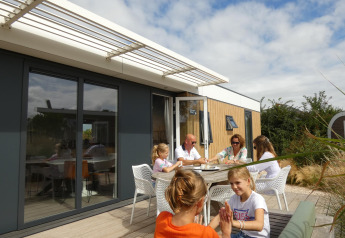 Familie entspannt sich im Freien am Dune Lodge Family bei Camping Zonneweelde in den Niederlanden.