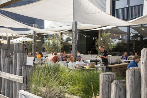 Buitenterras van Dune Lodge Family, Camping Zonneweelde, Nederland, met mensen en bediening.