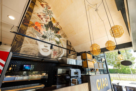 Interior view of Dune Lodge Family at Camping Zonneweelde with art mural, modern lights and large 'CIAO' sign.