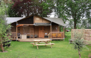 Tienda Safari Ranger DeLuxe con porche y mesas en césped del Camping Vossenberg en los Países Bajos.