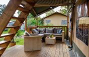 Terraza de madera con zona lounge en tienda Safari tent Ranger DeLuxe en Camping Vossenberg, Países Bajos.