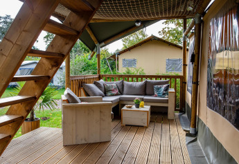 Terrazza in legno con area salotto nella tenda Safari Ranger DeLuxe al Camping Vossenberg, Paesi Bassi.
