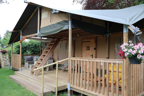 Tienda safari Ranger DeLuxe con porche de madera y flores en Camping Vossenberg en los Países Bajos.