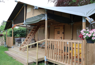 Safari tent Ranger DeLuxe with wooden porch and flowers at Camping Vossenberg in the Netherlands.