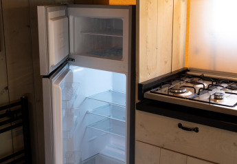 Cucina con frigorifero aperto nella tenda Safari Ranger DeLuxe al Camping Vossenberg, Paesi Bassi.