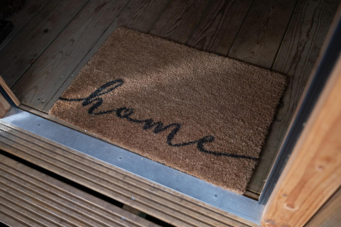 Doormat with the word 'home' at the entrance of Safari tent Ranger DeLuxe with hot tub at Camping Vossenberg.