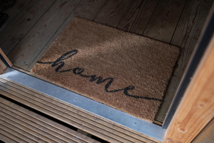 Felpudo con la palabra 'home' en la entrada de la tienda Safari Ranger DeLuxe con jacuzzi en Camping Vossenberg.