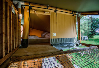 Innenansicht eines Safari-Zeltes Ranger DeLuxe mit Bett und Holzboden auf Camping Vossenberg, Niederlande.