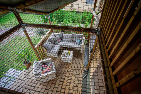 Vista superior de una terraza cubierta con muebles de jardín modernos y red de seguridad en Camping Vossenberg.