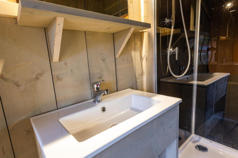Moderno lavabo y ducha en el baño de la tienda safari Ranger DeLuxe en Camping Vossenberg, Países Bajos.