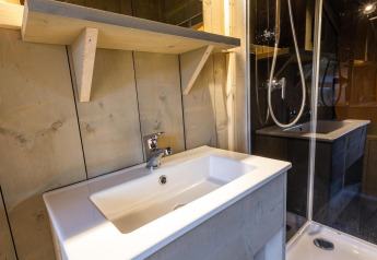 Lavabo e doccia moderni nel bagno della tenda Safari Ranger DeLuxe al Camping Vossenberg, Paesi Bassi.