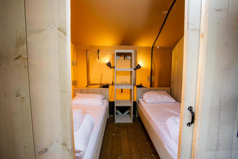 Vista interior de la tienda Safari Ranger DeLuxe con dos camas individuales en Camping Vossenberg, Países Bajos.