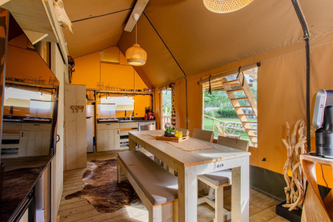 Interior de la tienda safari Ranger DeLuxe con mesa comedor y cocina en Camping Vossenberg, Países Bajos.