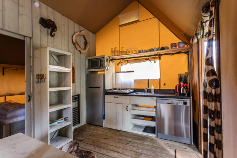 Vista interior de la tienda Safari Ranger DeLuxe con cocina y dormitorio en Camping Vossenberg, Países Bajos.