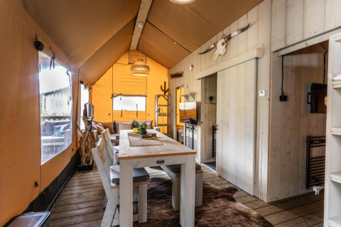 Vista interior de la tienda Safari Ranger DeLuxe con mesa de comedor de madera y decoración rústica.
