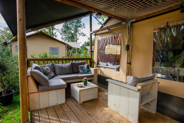 Buitenlounge bij Safari tent Ranger DeLuxe met banken en stoelen op Camping Vossenberg in Nederland.