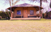 Tienda safari Cottage Kaa en Camping Vossenberg, Países Bajos, con terraza de madera y mesa de picnic.